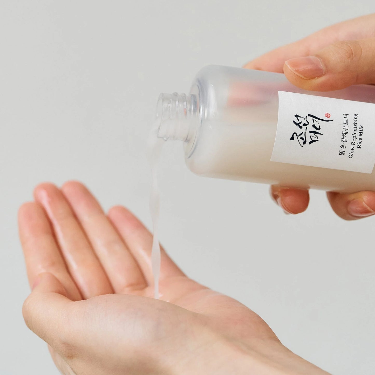 Beauty of Joseon Glow Replenishing Rice Milk being poured into a hand, showcasing its hydrating texture.